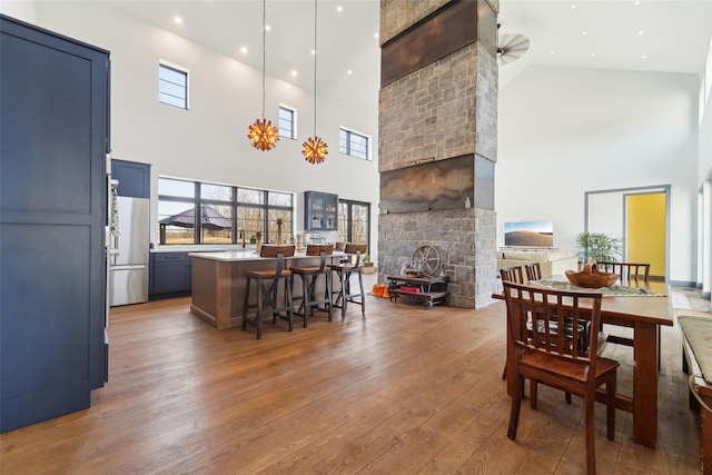 dining area with hardwood / wood-style floors, plenty of natural light, and a stone fireplace
