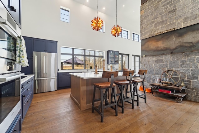 kitchen with a kitchen breakfast bar, light countertops, light wood finished floors, a wealth of natural light, and appliances with stainless steel finishes