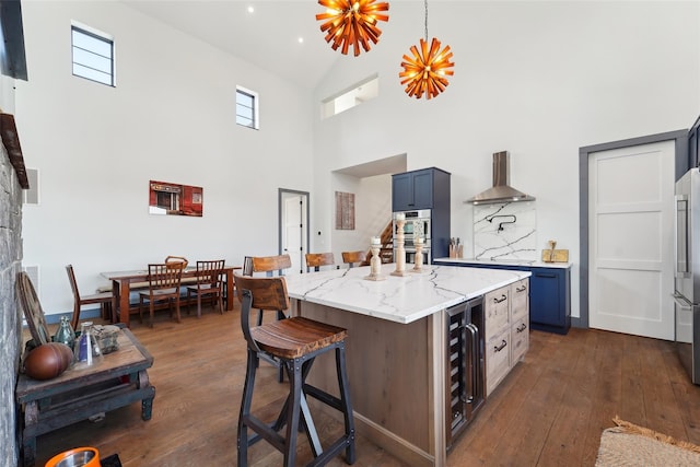 kitchen featuring a kitchen bar, dark wood-type flooring, wine cooler, wall chimney range hood, and appliances with stainless steel finishes
