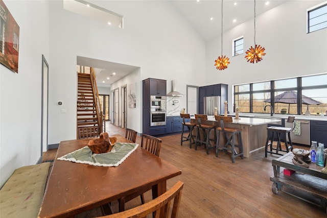 dining area featuring a towering ceiling, dark wood-type flooring, a healthy amount of sunlight, and stairway