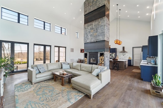 living room featuring a large fireplace, plenty of natural light, a high ceiling, and wood-type flooring