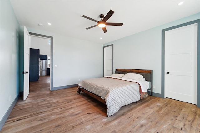bedroom featuring baseboards, light wood-style flooring, recessed lighting, and freestanding refrigerator