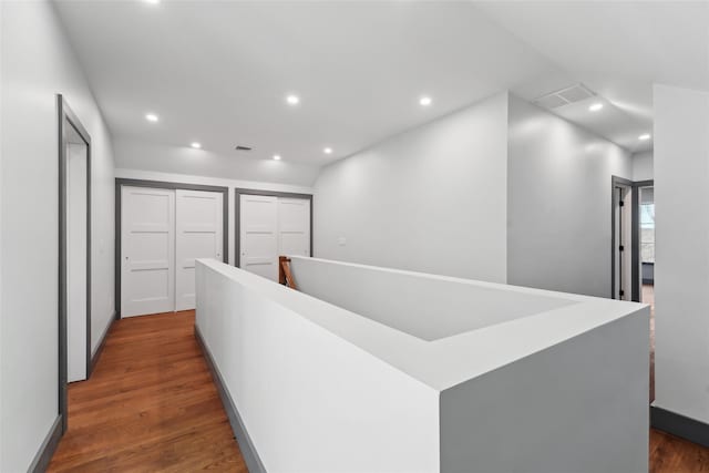 hall featuring an upstairs landing, visible vents, recessed lighting, and dark wood finished floors