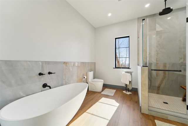 full bath featuring tile walls, toilet, a shower stall, a soaking tub, and wood finished floors