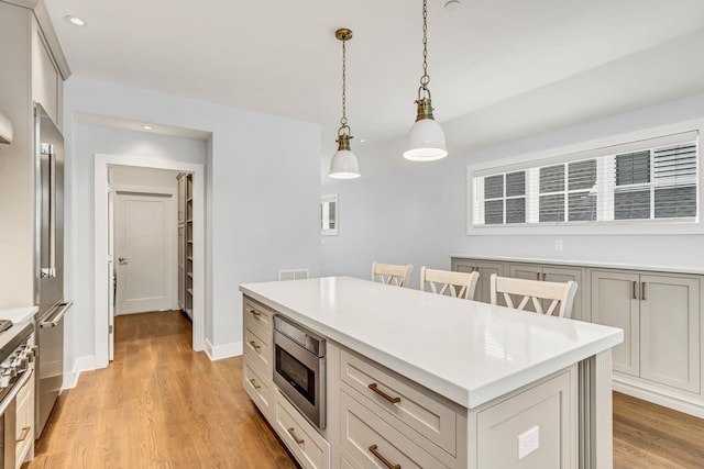 kitchen featuring pendant lighting, a breakfast bar area, a center island, light hardwood / wood-style floors, and stainless steel appliances