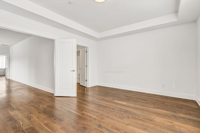 spare room featuring dark wood-type flooring and a raised ceiling