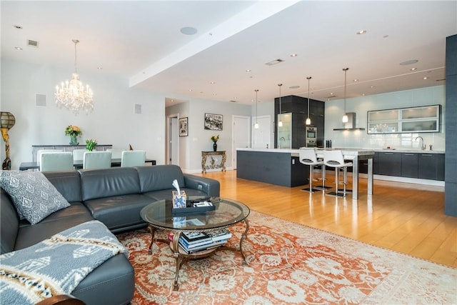 living room featuring sink, a notable chandelier, and light hardwood / wood-style flooring