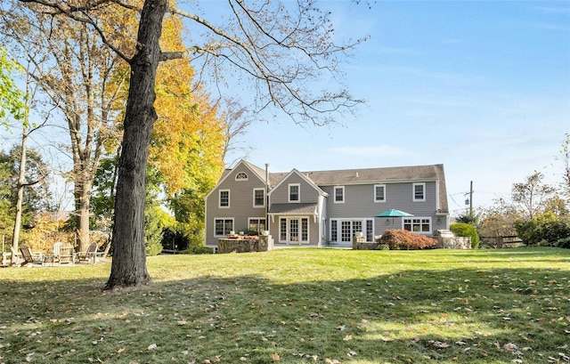 back of property with french doors and a lawn