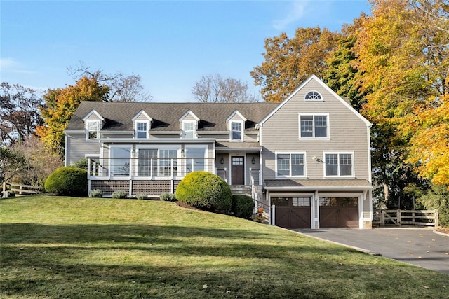 view of front facade featuring driveway, an attached garage, fence, and a front lawn