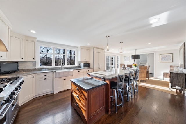 kitchen featuring stainless steel appliances, light stone counters, dark wood-type flooring, and a sink