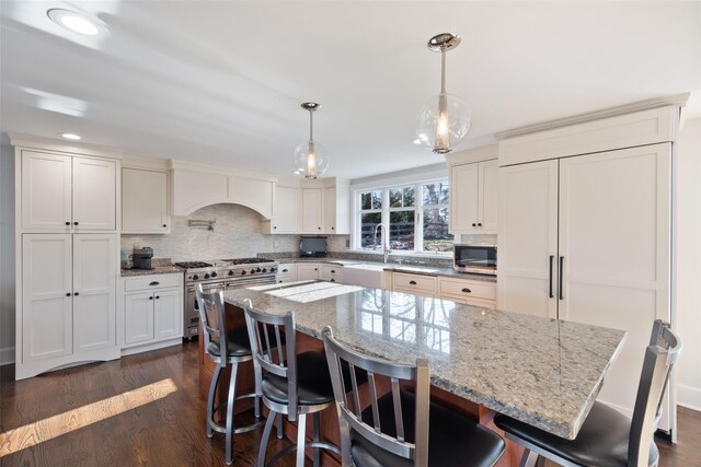 kitchen with appliances with stainless steel finishes, dark wood-style flooring, backsplash, and a center island