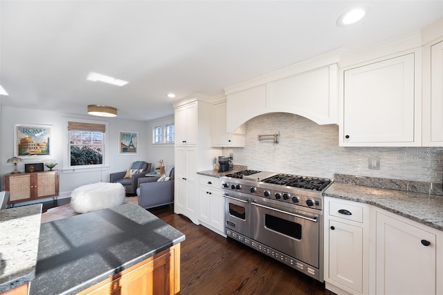 kitchen featuring range with two ovens, tasteful backsplash, dark wood-type flooring, open floor plan, and white cabinetry