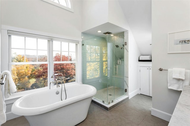 full bath featuring a stall shower, tile patterned flooring, baseboards, and a soaking tub