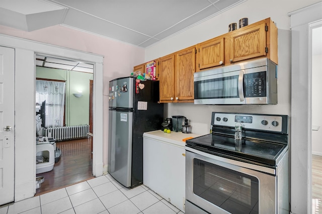 kitchen with light tile patterned floors, radiator heating unit, and stainless steel appliances