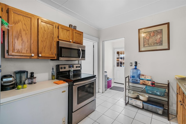 kitchen featuring light tile patterned floors, crown molding, and stainless steel appliances