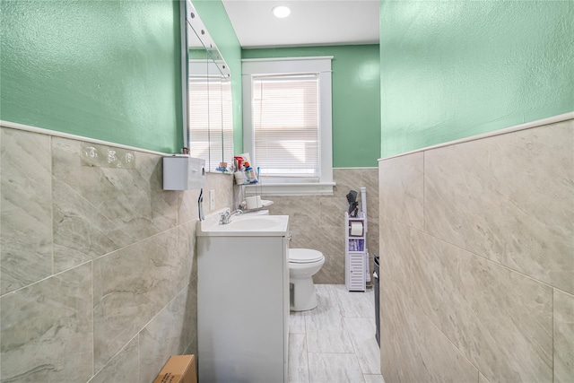 bathroom with vanity, tile walls, and toilet