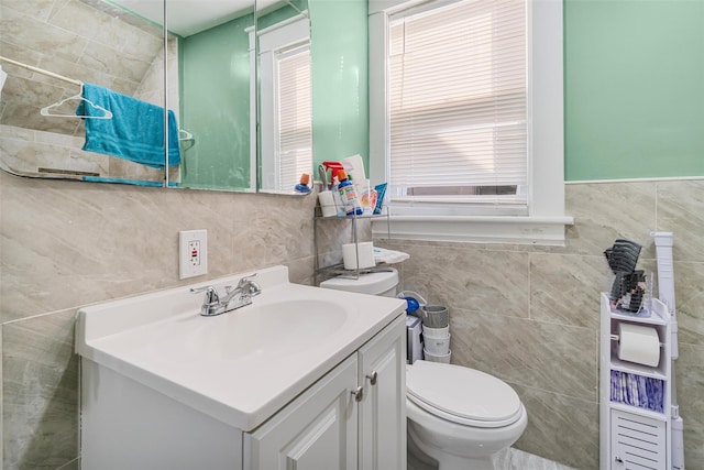 bathroom featuring vanity, toilet, and tile walls