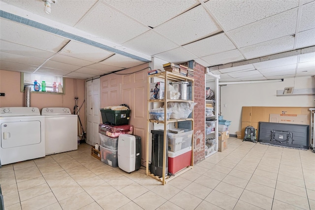 basement featuring light tile patterned flooring, a paneled ceiling, and separate washer and dryer