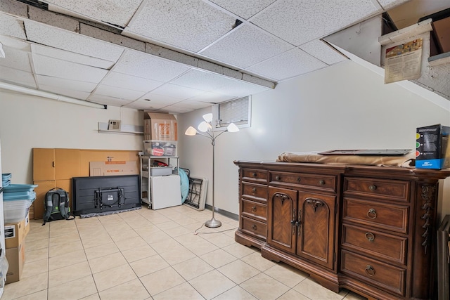 basement featuring a paneled ceiling and light tile patterned floors