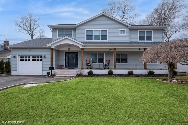 traditional-style home featuring a porch, a front yard, driveway, and a garage