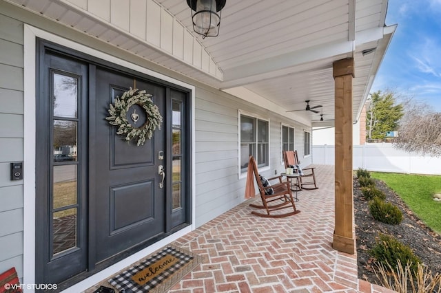 doorway to property with covered porch and fence