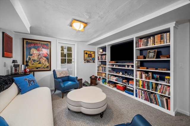 sitting room featuring a textured ceiling, carpet floors, built in shelves, and baseboards