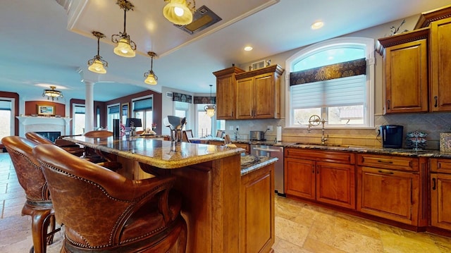 kitchen with dishwasher, stone tile floors, a fireplace, a kitchen breakfast bar, and a sink