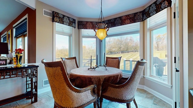 dining room with baseboards, visible vents, and stone tile flooring