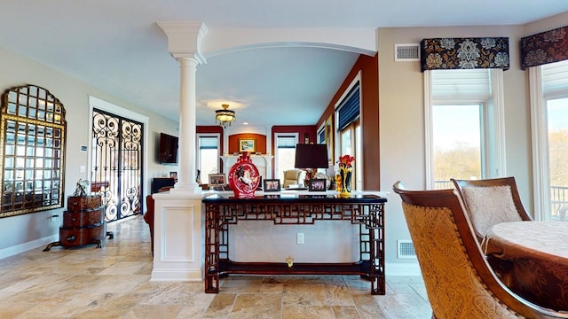 dining space featuring stone tile floors, visible vents, and decorative columns