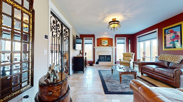 living room featuring stone tile flooring, a fireplace with raised hearth, and a healthy amount of sunlight