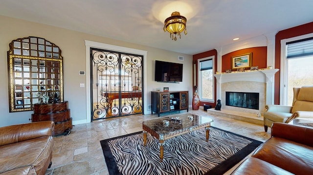 living area featuring stone tile floors, recessed lighting, baseboards, and a high end fireplace