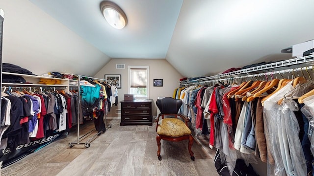 spacious closet with visible vents, lofted ceiling, and wood finished floors