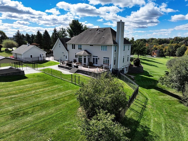 rear view of house featuring a yard, a chimney, and fence