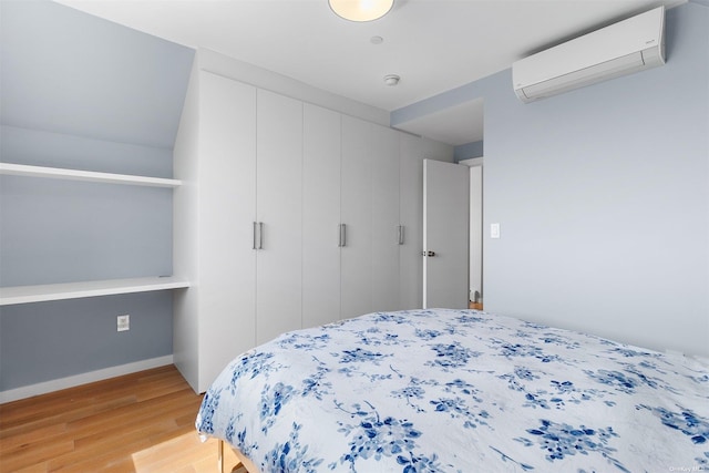 bedroom with a wall mounted air conditioner, wood-type flooring, and a closet