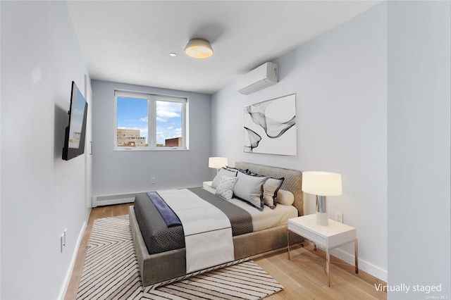 bedroom with light hardwood / wood-style floors and an AC wall unit