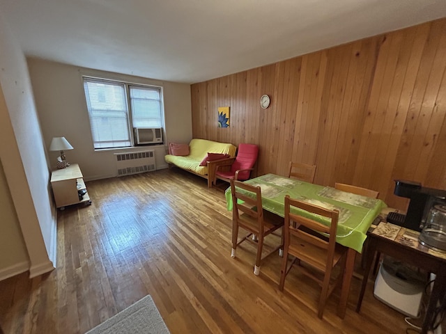 living area with hardwood / wood-style flooring, radiator, and wood walls