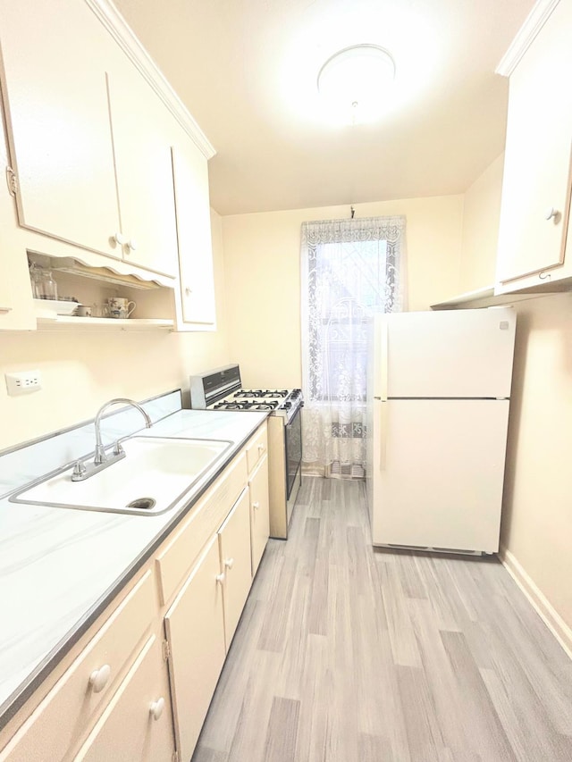 kitchen with sink, range with gas cooktop, light hardwood / wood-style flooring, white refrigerator, and white cabinets