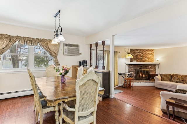 dining area featuring dark hardwood / wood-style flooring, a brick fireplace, a wall unit AC, and a baseboard radiator