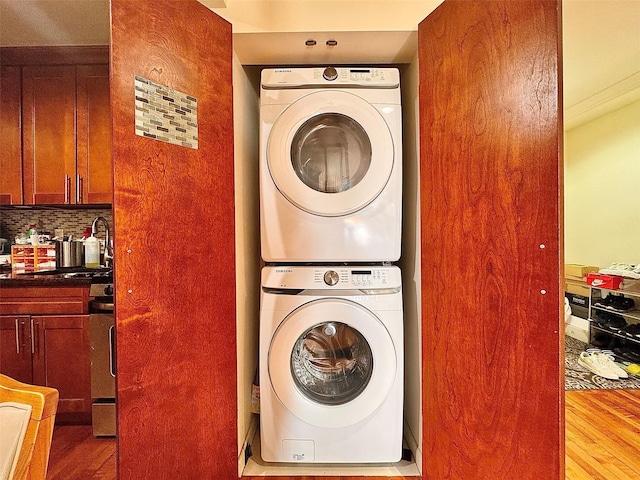 laundry room with stacked washing maching and dryer, sink, and light wood-type flooring