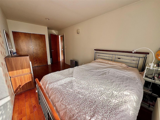 bedroom with dark hardwood / wood-style flooring and a closet