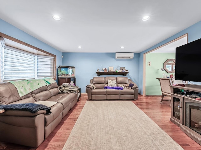 living area with light wood-style floors, an AC wall unit, and recessed lighting