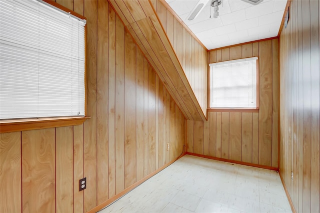 additional living space featuring ceiling fan, light floors, wood walls, and baseboards