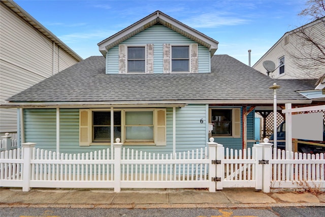 view of front of house featuring a shingled roof, a fenced front yard, and a gate