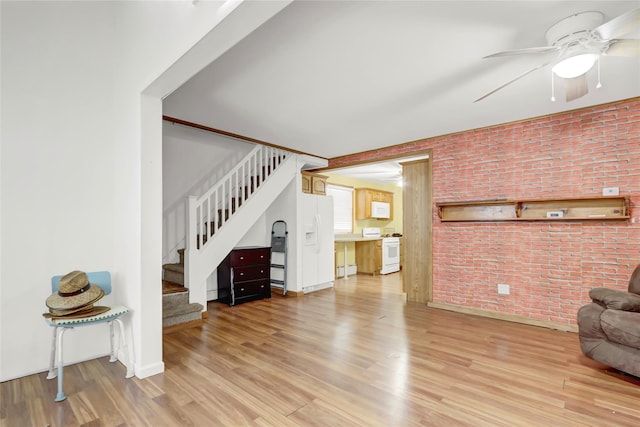 living area featuring light wood-style floors, stairway, and brick wall