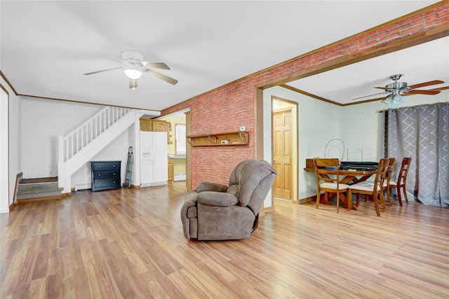 living room featuring light wood-style floors, ceiling fan, stairway, and ornamental molding