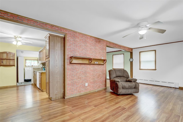 sitting room with a ceiling fan, light wood-type flooring, brick wall, and baseboard heating