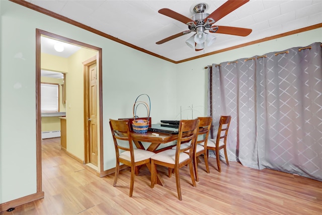 dining space featuring baseboards, a ceiling fan, ornamental molding, light wood-style floors, and a baseboard heating unit