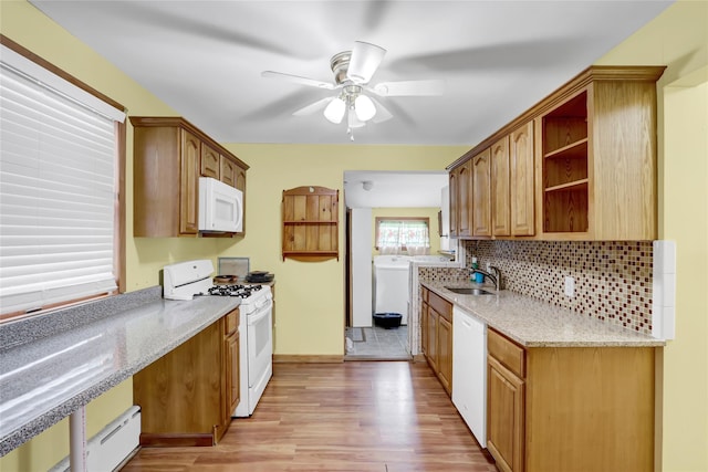 kitchen featuring white appliances, tasteful backsplash, light stone counters, light wood-style floors, and a sink