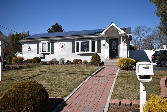 view of front of property with roof mounted solar panels and a front yard