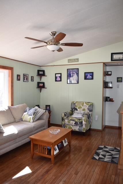 living area with vaulted ceiling, wood-type flooring, and a ceiling fan